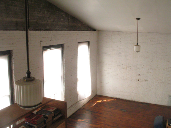Photograph from sleeping loft showing the hardwood floors and deco lights