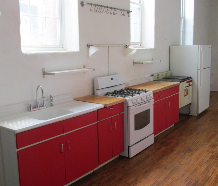 Photograph showing the butcher block counters farm house sink and 5 burner stove with grill. in the loftss kitchen
